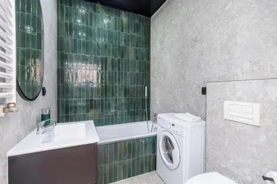 a green tiled bathroom with a washing machine and a sink at Nowoczesny apartament w ścisłym centrum Krakowa - by Upstairs in Kraków