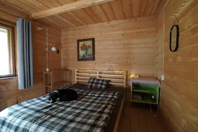 a dog laying on a bed in a cabin at Dom na końcu świata in Ochotnica Górna