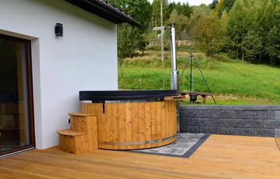 a wooden tub sitting on a deck next to a building at Leśna Muzyka Apartment Limanowa in Limanowa
