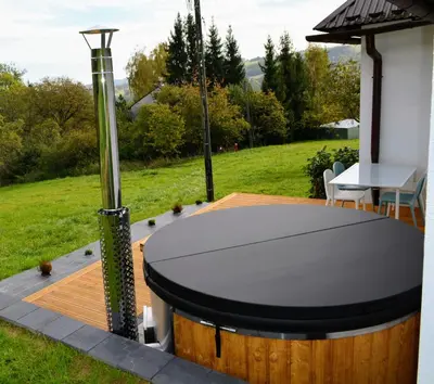 a hot tub on a deck with a table at Leśna Muzyka Apartment Limanowa in Limanowa