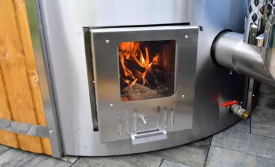 a metal oven with a fire in it at Leśna Muzyka Apartment Limanowa in Limanowa