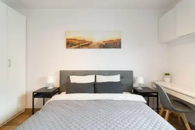a white bedroom with a bed and a desk at Zabłocie Apartament Oasis in Kraków