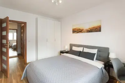 a white bedroom with a bed and a chair at Zabłocie Apartament Oasis in Kraków