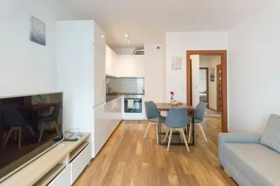 a living room and kitchen with a couch and a table at Zabłocie Apartament Oasis in Kraków