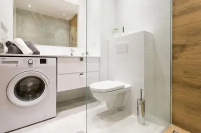 a white bathroom with a toilet and a washing machine at Zabłocie Apartament Oasis in Kraków