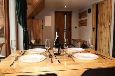 a wooden table with a bottle of wine and glasses at Domek Parzenica Nowy Targ in Nowy Targ