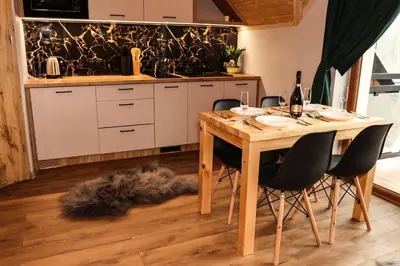 a kitchen with a wooden table with chairs and wine glasses at Domek Parzenica Nowy Targ in Nowy Targ