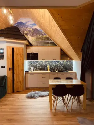 a kitchen with a table and chairs in a room at Domek Parzenica Nowy Targ in Nowy Targ
