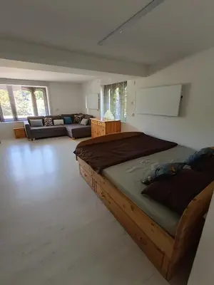 a bedroom with a large bed and a living room at Agroturystyka Rudy Kocur Różana 24 Jaroszowice in Jaroszowice