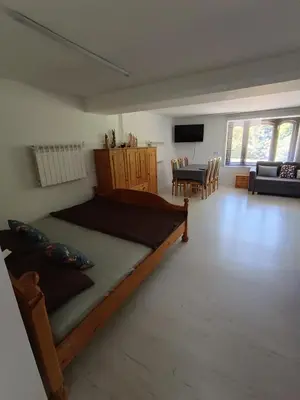 a bedroom with a large bed and a living room at Agroturystyka Rudy Kocur Różana 24 Jaroszowice in Jaroszowice
