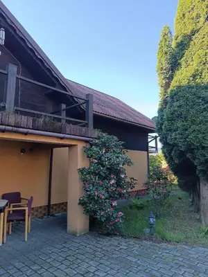 a building with a balcony and a table and a bush at Agroturystyka Rudy Kocur Różana 24 Jaroszowice in Jaroszowice