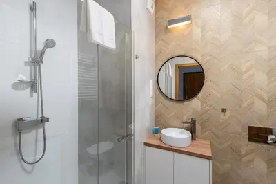 a bathroom with a shower and a sink and a mirror at Cracow Novum Apartment #58 by BookingHost in Kraków