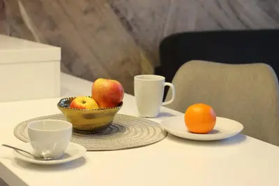 a table with a bowl of fruit and two cups at VIVA LILA Apartment, FREE PARKING, close to Vistula River - by Homelike Krakow in Kraków