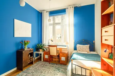 a bedroom with blue walls and a bed and a desk at Botaniczny Pokój in Kraków