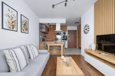 a living room with a couch and a kitchen at Near EXPO Cracow Elegant Apartment by Noclegi Renters in Kraków