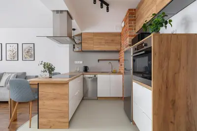 a kitchen with white cabinets and a brick wall at Near EXPO Cracow Elegant Apartment by Noclegi Renters in Kraków