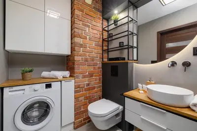 a bathroom with a white washing machine and a brick wall at Near EXPO Cracow Elegant Apartment by Noclegi Renters in Kraków