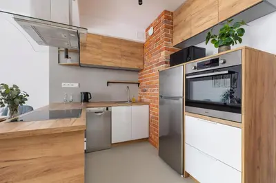 a kitchen with stainless steel appliances and a brick wall at Near EXPO Cracow Elegant Apartment by Noclegi Renters in Kraków