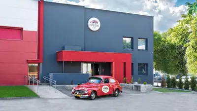 an old red car parked in front of a building at Automobil Hotel in Kraków