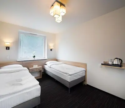 a hotel room with two beds and a window at Automobil Hotel in Kraków