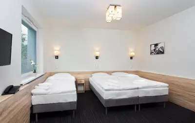 a room with three beds and a flat screen tv at Automobil Hotel in Kraków
