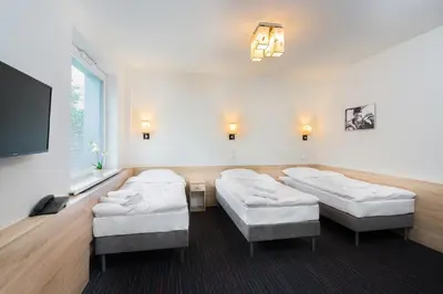 a hospital room with four beds and a flat screen tv at Automobil Hotel in Kraków