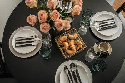 a black table with white plates and a basket of pastries at Skawinska Suites by Fragola Apartments in Kraków