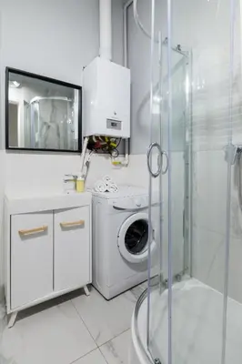 a white bathroom with a washing machine and a shower at Wonderful Apartments in the Center of Krakow in Kraków