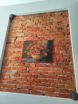 a painting of a vase of flowers on a brick wall at Apartament w centrum Brzeska 1 in Brzesko