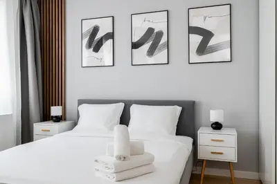 two beds in a bedroom with three pictures on the wall at Tauron Modern Studio by BookingHost in Kraków