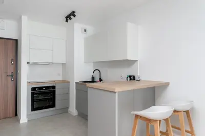 a kitchen with white cabinets and a counter top at Tauron Modern Studio by BookingHost in Kraków