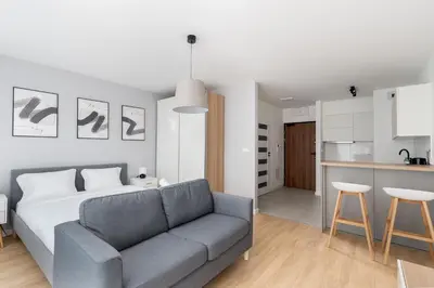 a living room with a couch and a kitchen at Tauron Modern Studio by BookingHost in Kraków