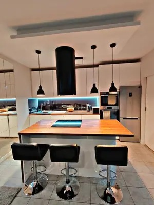a kitchen with a large wooden island with bar stools at Szlak Apartment Old Town in Kraków