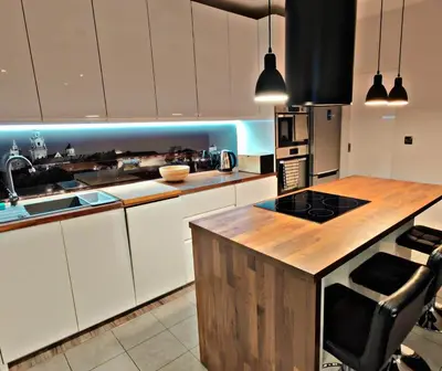 a kitchen with white cabinets and a wooden counter top at Szlak Apartment Old Town in Kraków