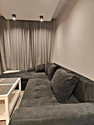 a living room with a large couch in front of a curtain at Szlak Apartment Old Town in Kraków