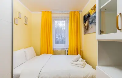 a bedroom with a bed and a window with yellow curtains at Kalinowe Green Apartment by BookingHost in Kraków