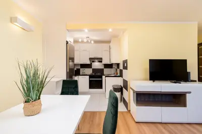 a kitchen and living room with a table and a tv at Kalinowe Green Apartment by BookingHost in Kraków