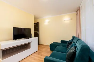 a living room with a green couch and a flat screen tv at Kalinowe Green Apartment by BookingHost in Kraków