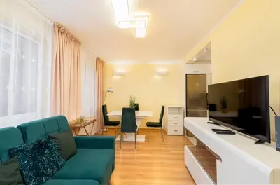 a living room with a blue couch and a television at Kalinowe Green Apartment by BookingHost in Kraków