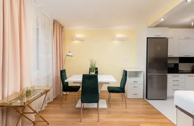 a kitchen and dining room with a table and chairs at Kalinowe Green Apartment by BookingHost in Kraków