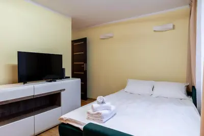 a bedroom with a bed and a flat screen tv at Kalinowe Green Apartment by BookingHost in Kraków