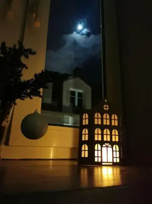 a candle shaped like a house in front of a window at Komfort w sercu Kazimierza in Kraków