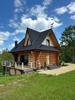a fire in front of a log cabin at night at Niedźwiedzi Zakątek in Sidzina