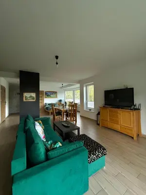 a living room with a green couch and a dining room at Apartament Guziczek2 in Nowy Targ