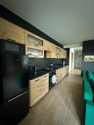 a kitchen with a black refrigerator and wooden cabinets at Apartament Guziczek2 in Nowy Targ