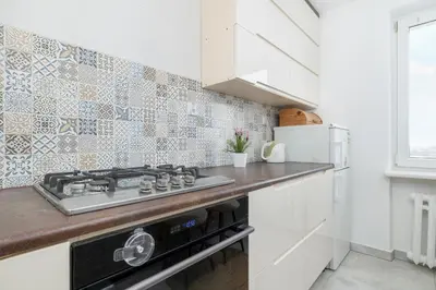 a kitchen with a stove top oven next to a refrigerator at Minimalist One Bedroom Apartment in Kraków Near Wawel by Noclegi Renters in Kraków
