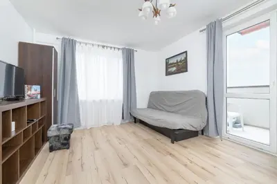 a living room with a chair and a television at Minimalist One Bedroom Apartment in Kraków Near Wawel by Noclegi Renters in Kraków