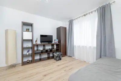 a white bedroom with a bed and a television at Minimalist One Bedroom Apartment in Kraków Near Wawel by Noclegi Renters in Kraków