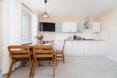 a kitchen with a table and chairs and a kitchen with white cabinets at Kraków Eagle Pharmacy Studio by Noclegi Renters in Kraków