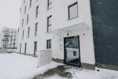 a white building with a door in the snow at Nowy Złocień Comfort Apartment by BookingHost in Kraków